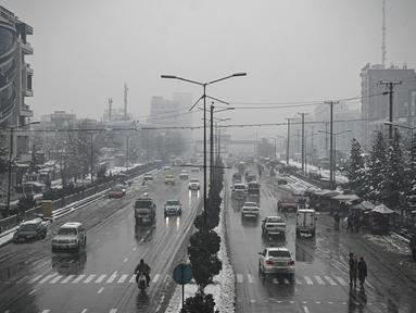 Komuter berjalan di sepanjang jalan saat hujan salju lebat di Kabul (4/1/2022). Beberapa kecelakaan terjadi pada Senin (3/1) di tengah kondisi lalu lintas yang kacau setelah hujan salju lebat. (AFP/Mohd Rasfan)