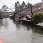 Warga melintasi jembatan apung saat banjir melanda perumahan Periuk Damai, Tangerang, Banten, Selasa (22/2/2021). Banjir setinggi 2,5 meter tersebut sudah terjadi selama 4 hari. (Liputan6.com/Angga Yuniar)