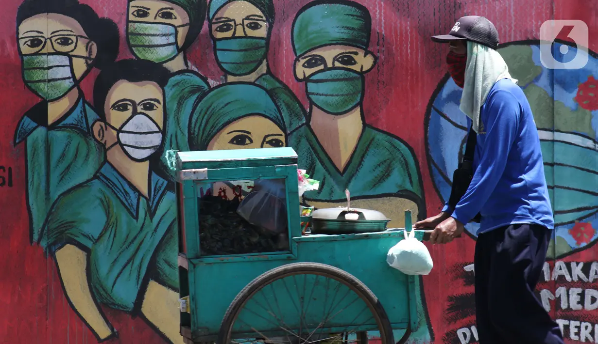 Pedagang melintas di depan mural tentang pandemi virus COVID-19 di Jalan Raya Jakarta-Bogor, Depok, Jawa Barat, Selasa (7/4/2020). Mural tersebut sebagai bentuk dukungan kepada tenaga medis yang menjadi garda terdepan menghadapi COVID-19 di Indonesia. (Liputan6.com/Helmi Fithriansyah)