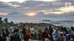 Wisatawan menikmati matahari terbit atau sunrise dengan latar belakang Candi Borobudur di Punthuk Setumbu, Karangrejo, Magelang, Jawa Tengah, Senin (16/5/2022). Punthuk Setumbu menjadi destinasi favorit di Jawa Tengah, terlebih saat libur Waisak yang terkenal dengan keindahan alam Candi Borobudur dan sekitarnya saat matahari terbit. (merdeka.com/Iqbal S. Nugroho)