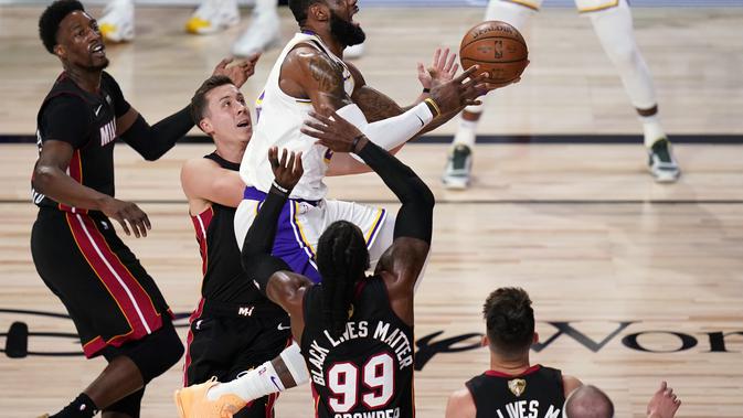 Pemain Los Angeles Lakers LeBron James melawan pertahanan Miami Heat saat mencoba memasukkan bola ke keranjang pada Gim 6 Final NBA di Lake Buena Vista, Florida, Senin (12/10/2020). (AP Photo / John) Raoux)