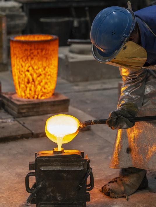 Pematung menuangkan logam cair untuk membuat medali dengan Beruang Berlinale, salah satu piala Festival Film Internasional Berlin di pengecoran Noack di Berlin, 25 Januari 2022. Kompetisi film Berlin edisi 2022 akan berlangsung dari 10 - 16 Februari secara tatap muka. (Hannibal Hanschke/POOL/AFP)