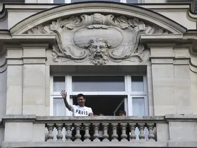Bintang sepak bola Argentina, Lionel Messi melambaikan tangan kepada para fans dari balkon hotelnya di Paris, Selasa (10/8/2021). Lionel Messi telah mencapai kesepakatan dengan Paris Saint-Germain (PSG) mengenai kepindahan ke klub Prancis tersebut. (AP Photo/Adrienne Surprenant)