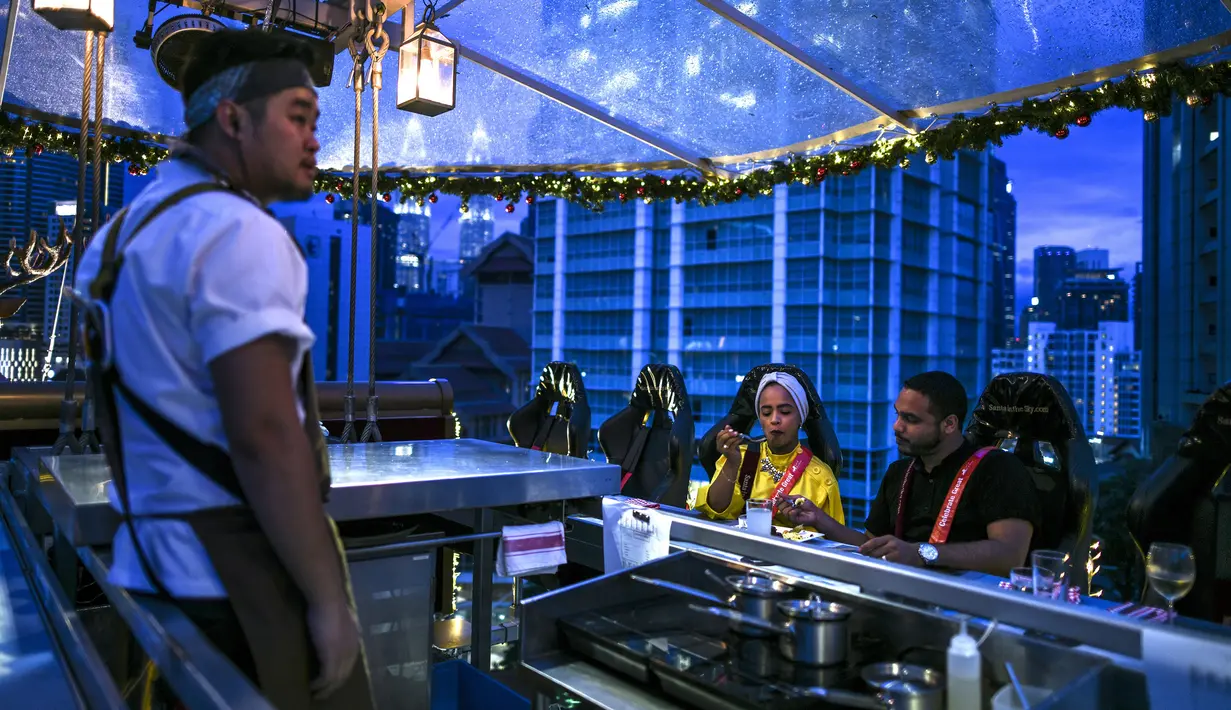 Pengunjung menyantap makan malam di restoran gantung dengan dekorasi kereta salju santa claus di Kuala Lumpur, Malaysia, Rabu (5/12). Restoran gantung ini merupakan yang pertama di Asia Tenggara. (MOHD RASFAN/AFP)