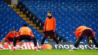 Bek Barcelona, Gerard Pique melakukan pemanasan bersama rekan-rekannya saat mengikuti sesi latihan di stadion Stamford Bridge di London, (19/2). Barcelona akan menghadapi Chelsea pada babak 16 besar Liga Champions. (AP Photo/Alastair Grant)