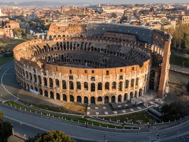 Foto udara pagi pada 30 Maret 2020, jalan-jalan sepi dan monumen Colosseum selama penerapan penutupan nasional atau lockdown di Roma. Roma menjelma bak kota mati pasca pemerintah Italia memberlakukan aturan lockdown di seantero wilayah untuk mencegah penyebaran virus corona. (Elio CASTORIA/AFP)