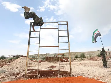 Pejuang dari Jaysh al-Izza (the Army of Glory) melompati rintangan saat melakukan latihan di kota Idlib, Suriah (9/4). Pejuang ini adalah afiliasi dari tentara Suriah yang didukung oleh Turki. (AFP/Omar Haj Kadour)