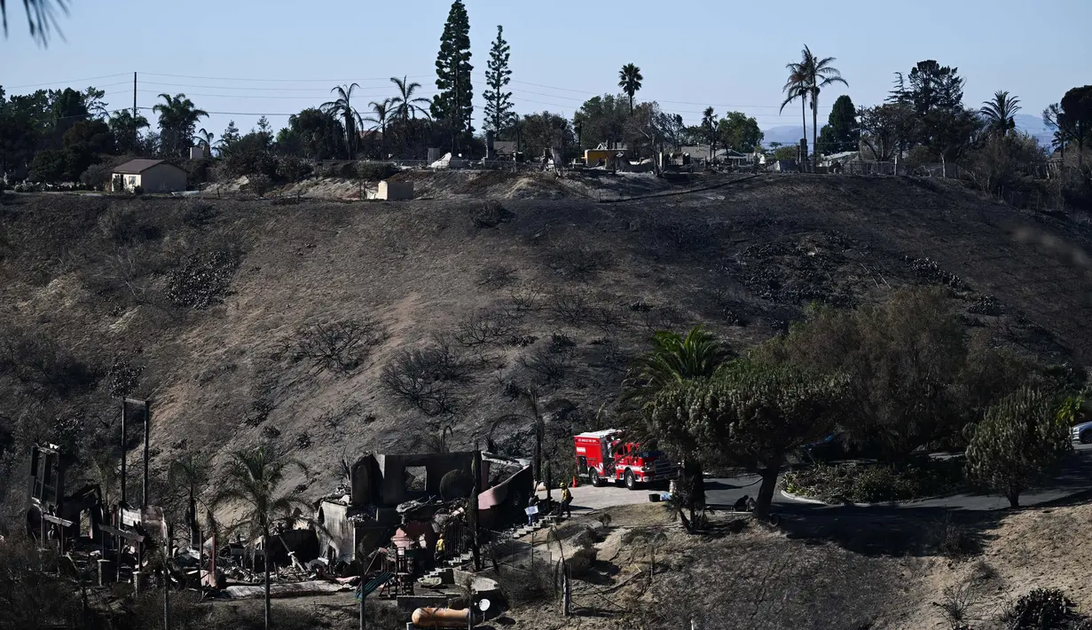 Petugas pemadam kebakaran mencari sisa titik api di lingkungan perumahan yang hancur akibat kebakaran hutan yang disebabkan oleh angin di Camarillo, California pada tanggal Jumat 8 November 2024. (Patrick T. Fallon/AFP)