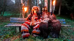 Sejumlah peserta mengenakan kostum iblis duduk sambil memegang obor bersiap mengikuti parade tardisional Perchtenlauf di Osterseeon dekat Munchen, Jerman (17/12). Tradisi ritual Pagan ini telah berusia 1.500 tahun (Reuters/Michaela Rehle)