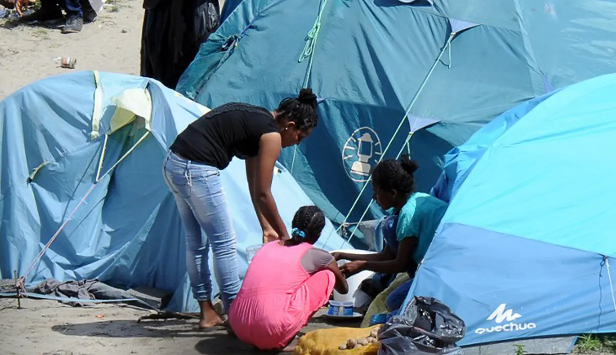 Sejumlah wanita berbincang di dekat tenda yang didirikan di sebuah kamp sementara di sekitar pelabuhan Calais, Prancis, Minggu (2/8/2015). Sebelumnya, ratusan imigran memaksa masuk Prancis melalui Terowongan Channel. (AFP PHOTO/FRANCOIS LO PRESTI)