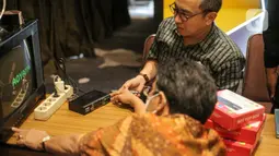 Petugas Kementerian Kominfo memberikan penjelasan penggunaan alat STB atau Set Top Box yang dibagikan secara gratis kepada warga di Posko Respon Cepat Penanganan Bantuan STB di Hotel Akmani, Jakarta, Kamis (3/11/2022). Untuk mempermudah masyarakat beralih kepada siaran TV digital, pemerintah telah menyediakan alat bantu siaran Set Top Box gratis kepada 6,7 juta keluarga miskin di Indonesia. (Liputan6.com/Faizal Fanani)