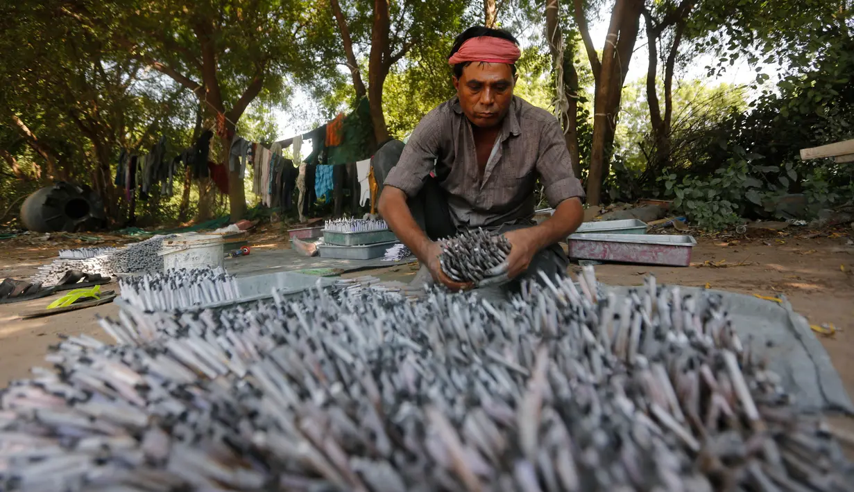Pekerja India menata gulungan kertas berisi bubuk mesiu membuat petasan di sebuah pabrik di pinggiran Ahmadabad, Selasa (15/10/2019).  Menjelang Festival Diwali atau Festival Cahaya, produsen petasan di india dibanjiri pesanan. (AP Photo/Ajit Solanki)
