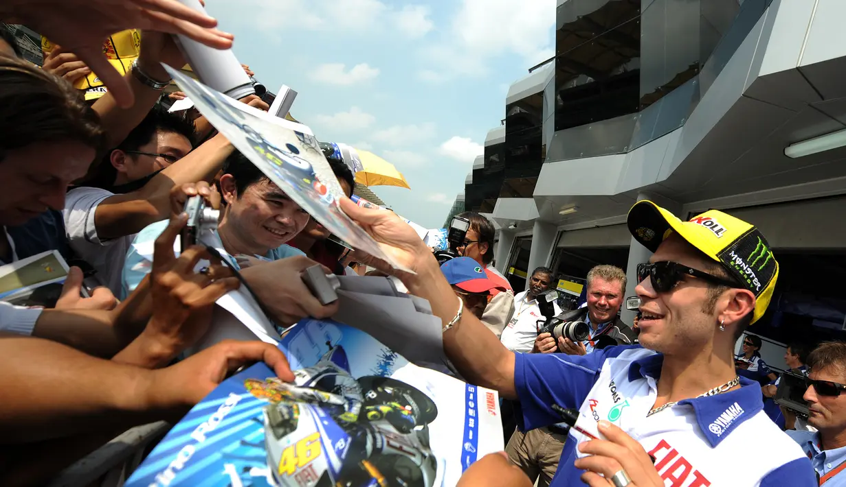 Tanda tangan yang diberikan oleh sang pembalap Valentino Rossi disambut meriah oleh para penggemarnya yang setia menunggu. Tak lupa ia selalu berikan senyuman ramah kepada para penggemar. (AFP/Bintang.com)