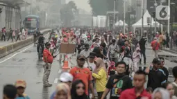 Petugas keamanan berjaga saat warga beraktivitas di car free day (CFD) kawasan Bundaran HI, Jakarta, Minggu (29/12/2019). Kendati tidak seramai saat cerah, warga yang berlari, jalan santai, atau swafoto masih menjadi pemandangan di area CFD usai hujan mengguyur Jakarta. (Liputan6.com/Faizal Fanani)