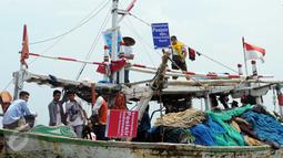 Sejumlah nelayan bersama aktivis Walhi menunjukkan poster berisi penolakan terhadap proyek reklamasi Teluk Jakarta saat upacara sedekah bumi yang lebih dikenal dengan sebutan Nadran di Muara Angke, Jakarta, Minggu (13/12/2015). (Liputan6.com/Helmi Afandi)