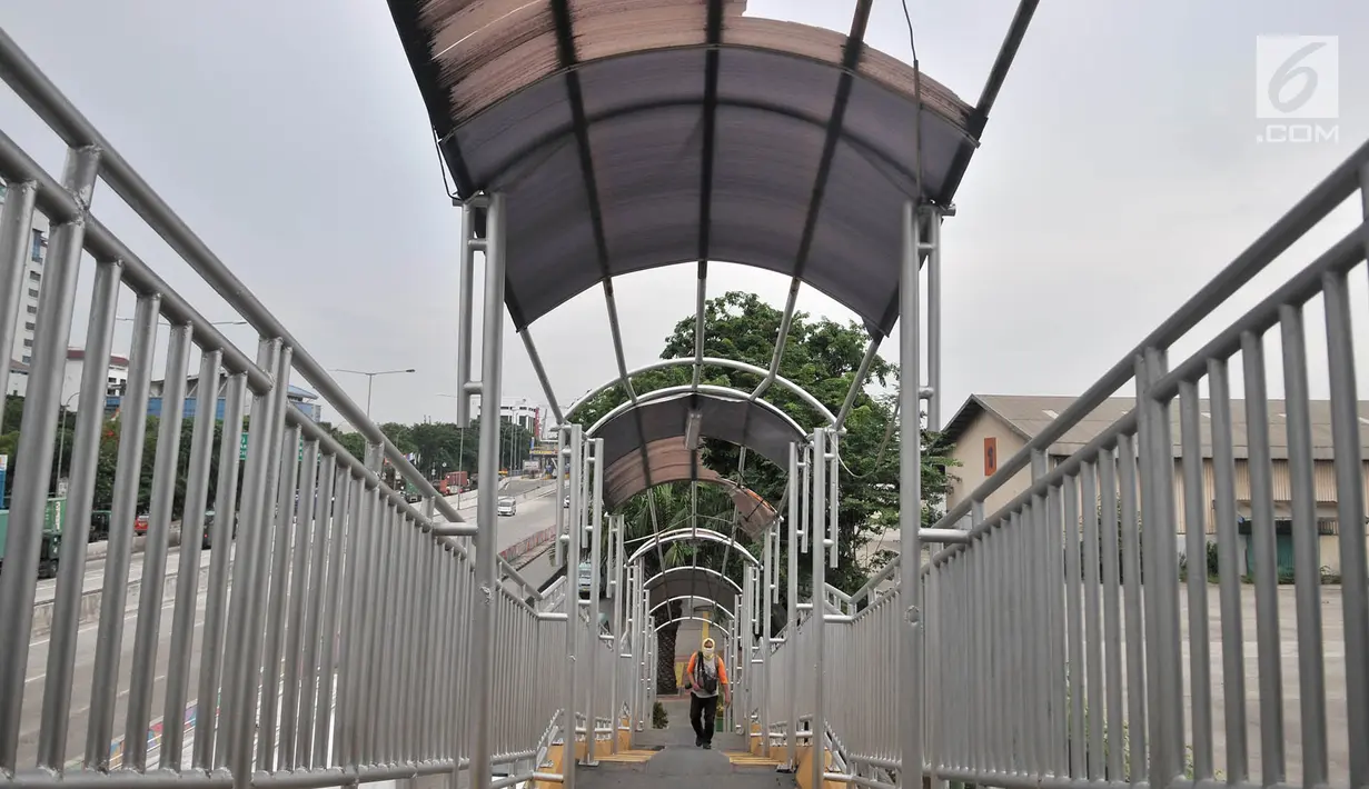 Pejalan kaki melintasi jembatan penyeberangan orang (JPO) di Jalan Yos Sudarso, Jakarta, Kamis (8/11). JPO akan semakin mengganggu kenyamanan dan keselamatan pejalan kaki apabila sedang hujan. (Merdeka.com/Iqbal Nugroho)