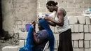 Seorang wanita saat dikepang rambutnya di pemukiman informal Elechi Phase 3 di Port Harcourt, Nigeria selatan (14/2). Nigeria akan mengadakan pemilihan presiden dan parlemen pada tanggal 16 Februari 2019. (AFP Photo/Yasuyoshi Chiba)