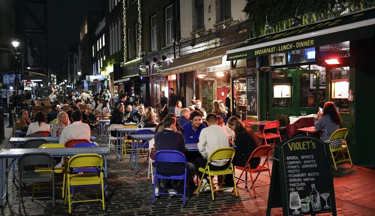 Orang-orang makan dan minum di luar di Soho, di London, Selasa (22/9/2020). Perdana Menteri Inggris, Boris Johnson, telah mengumumkan bahwa pub dan restoran tutup pada pukul 10 malam, karena lonjakan kasus virus corona di seluruh Inggris. (AP Photo / Alberto Pezzali)