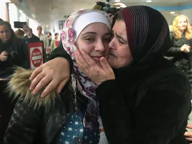 Pengungsi asal Suriah Baraa Haj Khalaf, disambut oleh ibunya Fattuom Bakir saat tiba di bandara Internasional O'Hare, AS, Rabu (7/2). Baraa dan keluarganya harus menjalani introgasi panjang agar bisa melewati otoritas bandara. (AFP Photo/ Scott Olson)