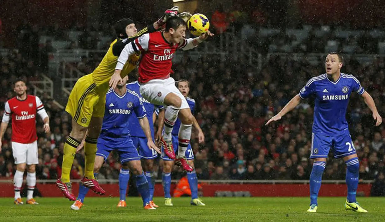 Kiper Chelsea Petr Cech duel udara dengan gelandang Arsenal Mesut Ozil pada pertandingan sepak bola Liga Inggris antara Arsenal vs Chelsea di Stadion Emirates, London (24/12/13). (AFP/Adrian Dennis)