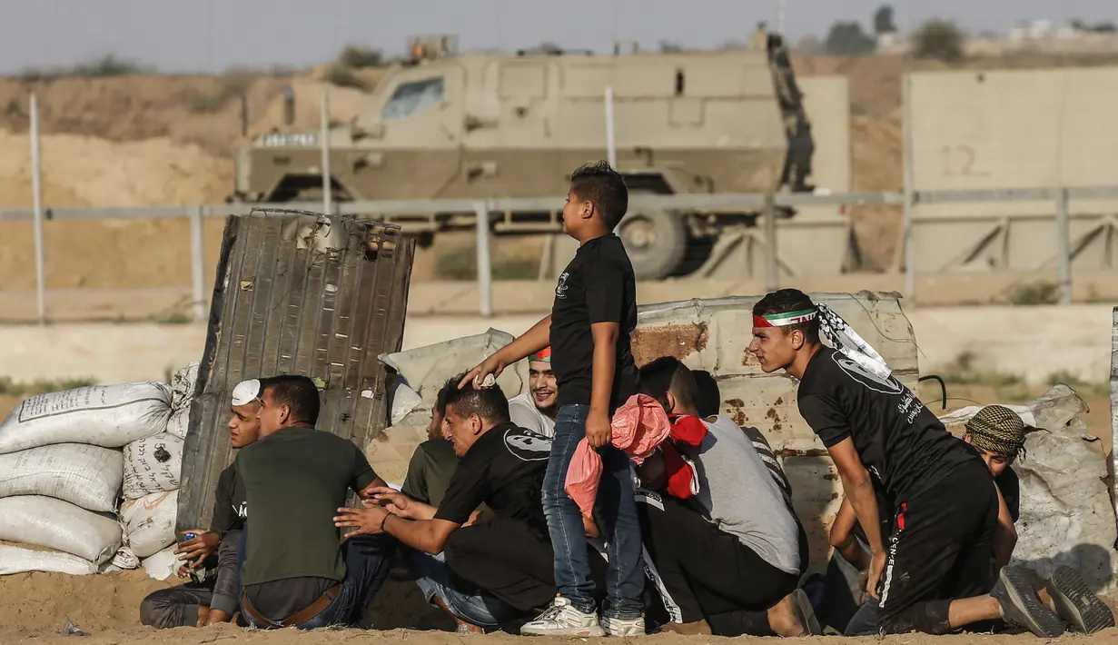 Warga Palestina berlindung dari pasukan Israel saat bentrok di Khan Yunis, Jalur Gaza, Jumat (13/9/2019). Kementerian Kesehatan Palestina mengatakan 55 warganya terluka oleh peluru tajam dan bom gas air mata pasukan Israel. (SAID KHATIB/AFP)