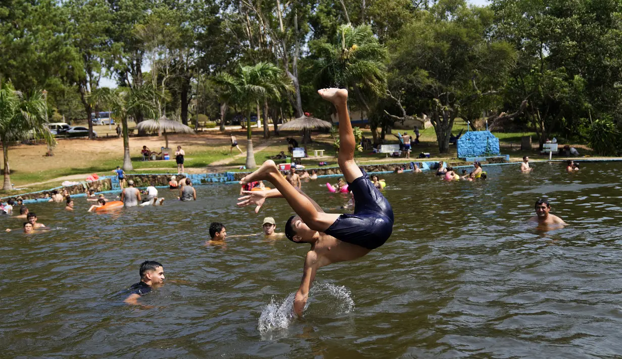 Orang-orang mendinginkan tubuh di sungai di tengah gelombang panas di Paraguari, Paraguay, Minggu (16/1/2022). Suhu Paraguay secara umum mencapai 41 derajat celsius. (AP Photo/Jorge Saenz)