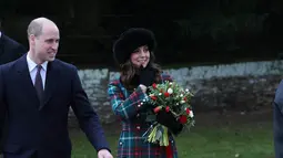 Pangeran William dan Kate Middleton seusai menghadiri kebaktian Hari Natal Kerajaan Inggris di Gereja St. Mary Magdalene, Sandringham, Senin (25/12). Kate tampil anggun dalam balutan pea coat bermotif tartan dengan nuansa hijau dari Miu Miu. (AP Photo)