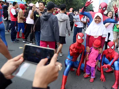 Sejumlah orang dengan kostum Spiderman berfoto bersama anak-anak di CFD Jalan MH Thamrin, Jakarta, Minggu (6/8). Mereka mengajak warga berswafoto sambil berdonasi untuk panti asuhan. (Liputan6.com/Fery Pradolo)