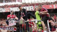 Pelatih Bayer Leverkusen, Xabi Alonso, memanjat tribun penonton saat merayakan gelar juara Bundesliga 2024 bersama suporter di BayArena, Sabtu (18/5/2024). (AP Photo/Martin Meissner)
