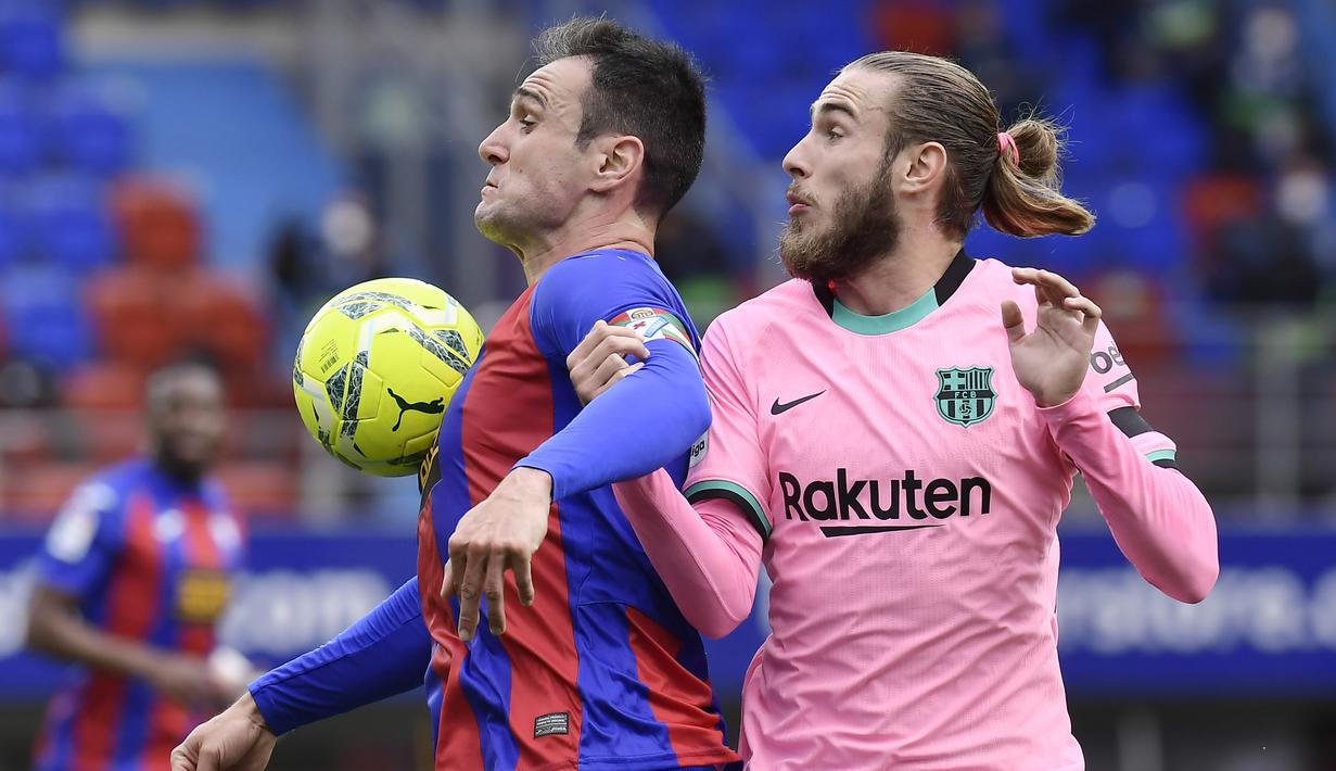 Pemain Barcelona, Oscar Mingueza, berebut bola dengan pemain Eibar, Kike Garcia pada laga Liga Spanyol di Stadion Ipurua, Sabtu (23/5/2021). Barcelona menang dengan skor 1-0. (AP/Alvaro Barrientos)