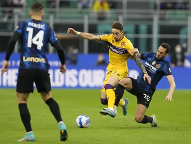 Gelandang Inter Milan, Hakan Calhanoglu (kanan) berusaha merebut bola dari pemain Fiorentina, Gaetano Castrovilli dalam pertandingan lanjutan Liga Serie A Italia di Stadion San Siro, di Milan, Italia, Minggu (20/3/2022). Inter Milan bermain imbang atas Fiorentina 1-1. (AP Photo/Antonio Calanni)