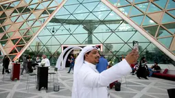 Pengunjung berswafoto dengan latar belakang teater bioskop pertama di King Abdullah Financial District Theatre, ibu kota Riyadh, Rabu (18/4). Peluncuran perdana bioskop Arab Saudi ini dihadiri oleh para tamu undangan. (AP/Amr Nabil)