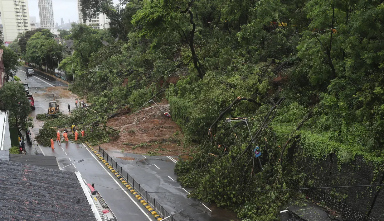 Petugas pemadam kebakaran membersihkan jalan setelah tanah longsor yang disebabkan oleh curah hujan di Mumbai, India, Rabu, (6/8/2020). Musim hujan India berlangsung dari Juni hingga September. (AP Photo / Rafiq Maqbool)