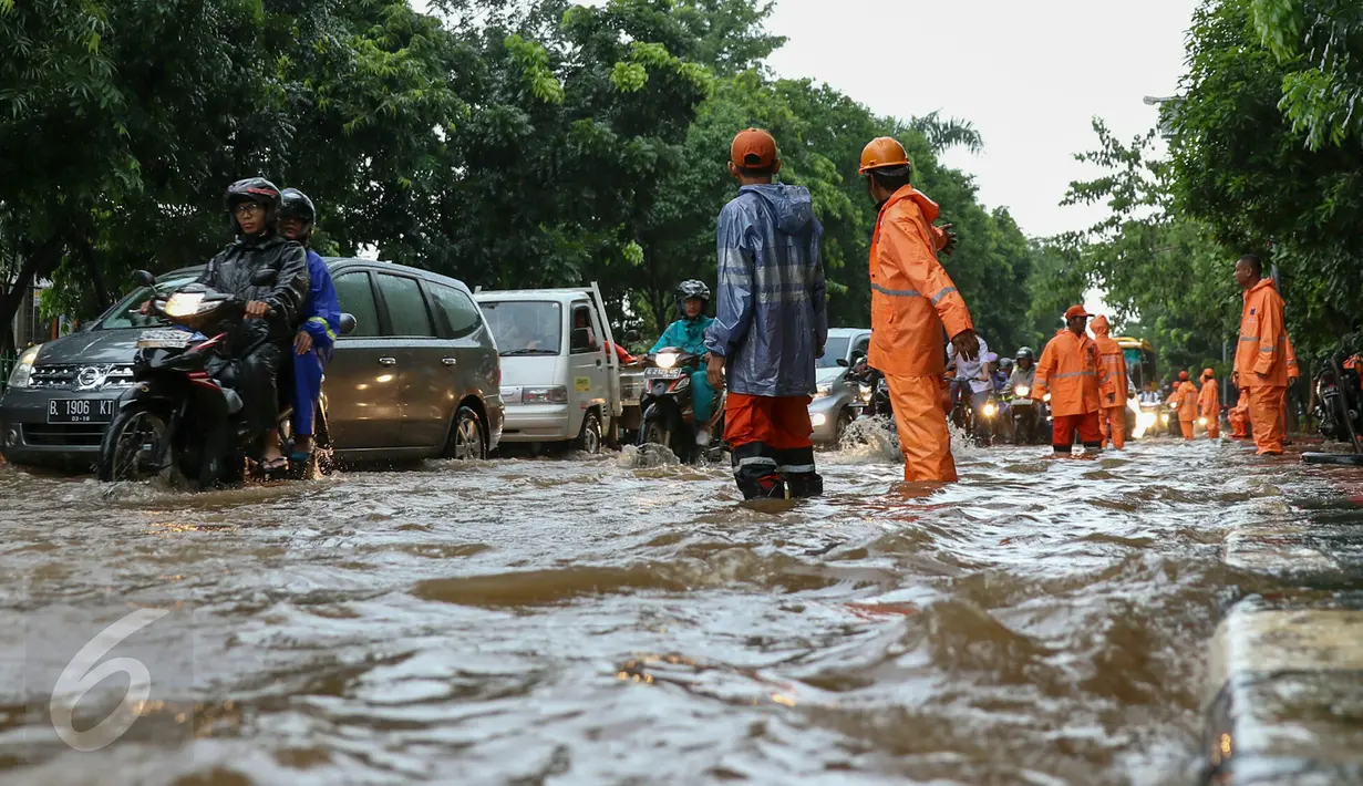 Petugas PPSU Srengseng Sawah melakukan pengaturan kendaraan yang melintas di jalan Lenteng Agung, Jakarta, (12/2). Akibat Hujan deras,  jalan Lenteng Agung tepat di depan Universitas Pancasila  tergenang banjir hingga 50 cm. (Liputan6.com/Yoppy Renato)
