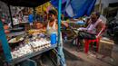 Seorang pedagang kaki lima menyiapkan makanan saat seorang pria makan di sebuah pasar grosir sayuran di Guwahati, India, Rabu (1/2/2023). Pemerintah Perdana Menteri India Narendra Modi meningkatkan belanja modal sebesar 33% untuk memacu pertumbuhan ekonomi dan menciptakan lapangan kerja menjelang pemilihan umum tahun depan. (AP Photo/Anupam Nath)