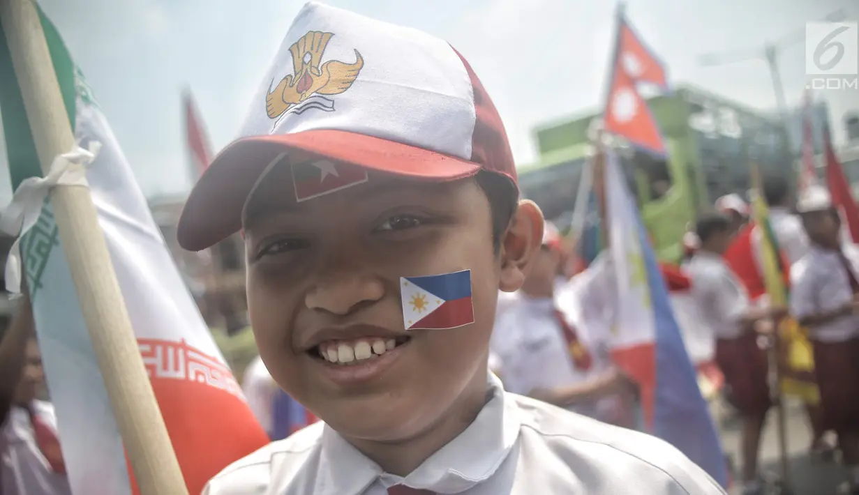 Seorang siswa SD mengenakan atribut bendera negara peserta Asian Games 2018 saat menyambut Kirab Obor di kawasan Jati Padang, Pasar Minggu, Rabu (15/8). Mereka memenuhi jalanan untuk menyaksikan langsung Pawai Obor Asian Games (Liputan6.com/Faizal Fanani)