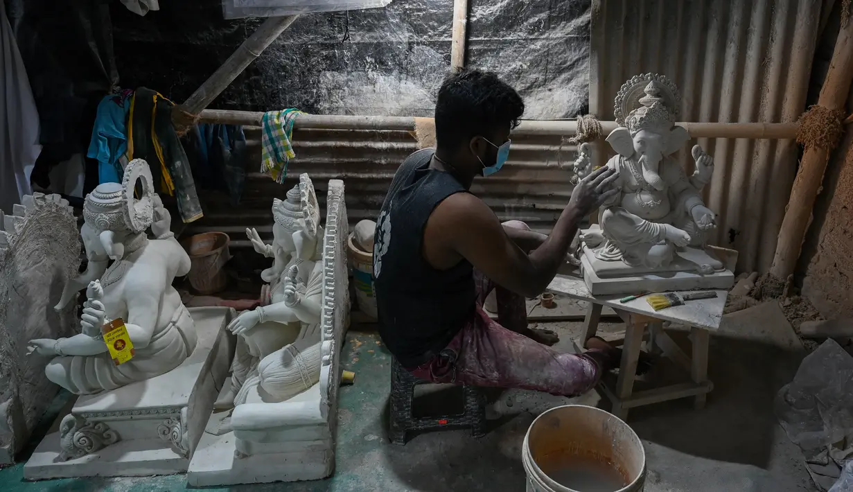 Perajin mengerjakan patung dewa Hindu berkepala gajah Lord Ganesha di sebuah lokakarya menjelang festival Ganesh Chaturthi di Mumbai (12/8/2021). Festival Ganesh Chaturthi adalah perayaan kelahiran Ganesha, dewa kebijaksanaan, kemakmuran, dan keberuntungan Hindu. (AFP/Punit Paranjpe)