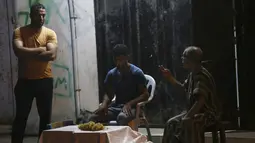 Seorang penjual anggur (tengah) menunggu pelanggan, sementara yang lain mengobrol dengannya selama penguncian yang diberlakukan selama pandemi virus corona, di kamp pengungsi Shati, di Kota Gaza, Selasa, (1/9/2020). (AP Photo/Adel Hana)