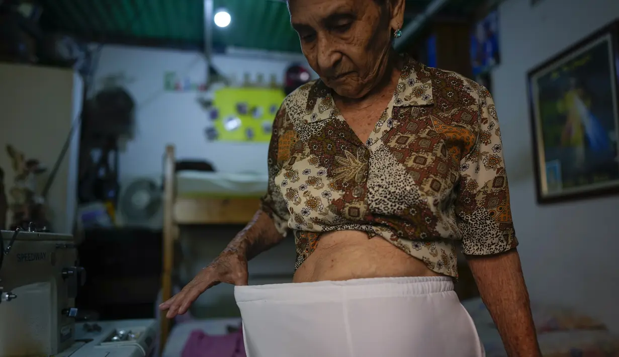 Candida Suarez menunjukkan berat badannya yang turun, ketika pandemi corona di Venezuela, 18 Agustus 2021. Suarez mengatakan uang pensiunnya yang setara dengan $2,47 tidak cukup untuk membeli makanan sehingga dia tinggal di rumah putrinya yang bermigrasi ke Argentina. (AP Photo/Ariana Cubillos)