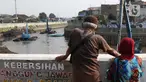 Warga menyaksikan proses pengerukan endapan tanah di aliran Sungai Ciliwung, Jakarta, Selasa (28/7/2020). Pengerukan endapan ini untuk memperlancar aliran air Sungai Ciliwung serta upaya pencegahan banjir saat musim hujan. (Liputan6.com/Helmi Fithriansyah)