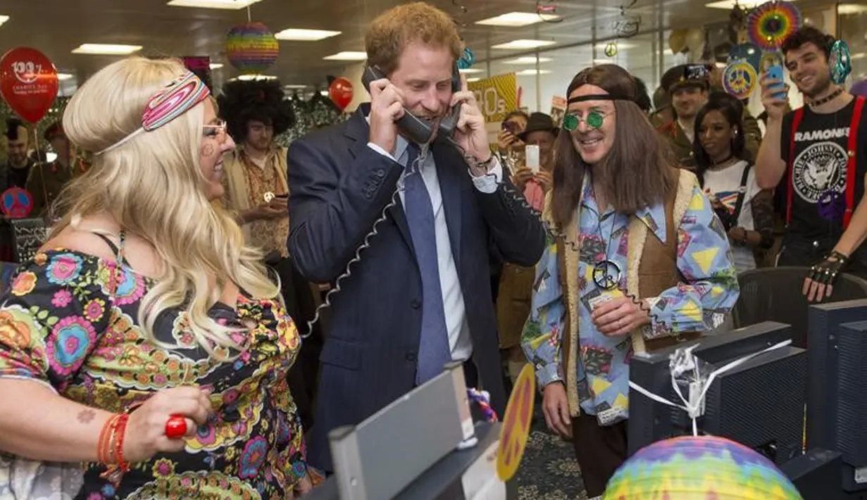 Pangeran Harry mengangkat dua telepon sekaligus saat menjadi broker dalam acara amal tahunan ICAP di London, Rabu (7/12). Pangeran Harry menjadi broker dadakan untuk mengumpulkan dana amal dari 60 kantor di seluruh dunia. (REUTERS/Geoff Pugh/Pool)