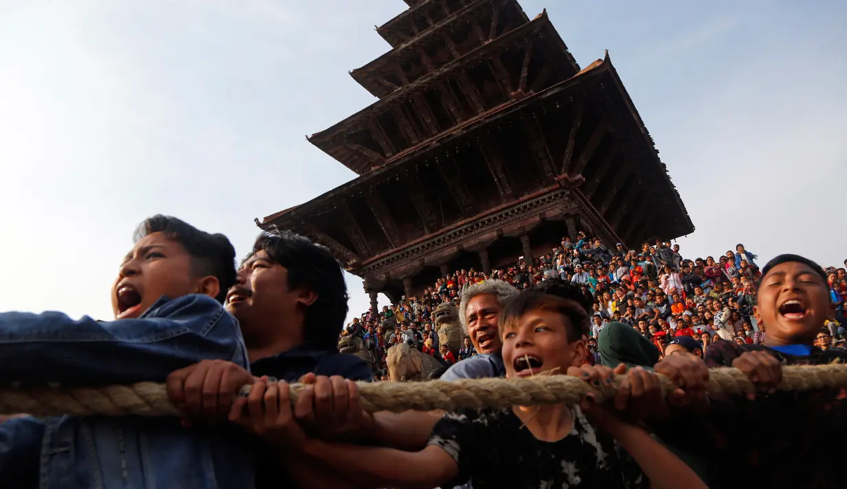 Sejumlah umat Hindu Nepal menarik kereta kayu dewa Bhairava saat festival Bisket Jatra di Bhaktapur, Nepal (10/4). Mereka menarik kereta kayu yang membawa dewa Hindu Bhairava ke lapangan terbuka. (AP Photo/Niranjan Shrestha)