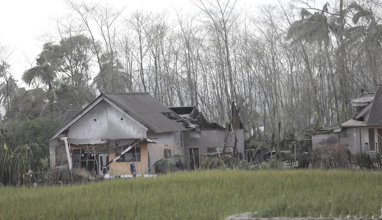 Warga memeriksa kerusakan di rumahnya di daerah yang terkena dampak letusan Gunung Semeru di Lumajang, Jawa Timur, Minggu (5/12/2021). Gunung Semeru memuntahkan kolom tebal abu, gas yang membakar dan lava menuruni lerengnya dalam letusan tiba-tiba yang dipicu oleh hujan lebat. (AP Photo/Trisnadi)