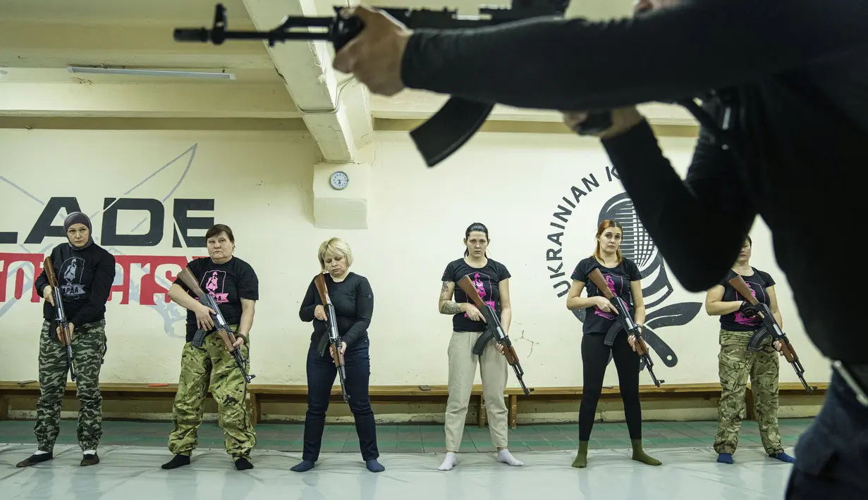 Seorang instruktur menunjukkan cara menggunakan senjata kepada sekelompok wanita selama pelatihan di Kharkiv, Ukraina (30/1/2022). Kharkiv hanya berjarak 40 kilometer (25 mil) dari puluhan ribu tentara Rusia yang berkumpul di perbatasan. (AP Photo/Evgeniy Maloletka)
