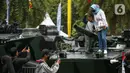 Warga berfoto di atas kendaraan milik TNI saat pameran alat utama senjata (alutsista) di Lapangan Monumen Nasional (Monas) Jakarta, Minggu (24/9/2023). (Liputan6.com/Faizal Fanani)
