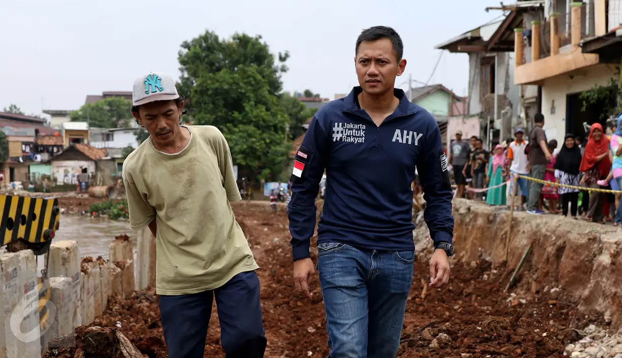 Bakal Cagub DKI, Agus Harimurti Yudhoyono bersama seorang warga menyusuri pinggiran Sungai Ciliwung di Bukit Duri, Jakarta, Kamis (20/10). Kunjungan Agus Yudhoyono untuk melihat langsung kondisi warga yang terkena gusuran. (Liputan6.com/Gempur M Surya)