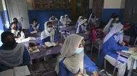 Siswa yang mengenakan masker menghadiri kelas di sebuah sekolah di Lahore (16/9/2021). Pemerintah Pakistan membuka kembali lembaga pendidikan yang ditutup sebagai tindakan pencegahan untuk mengekang penyebaran virus corona Covid-19. (AFP/Arif Ali)