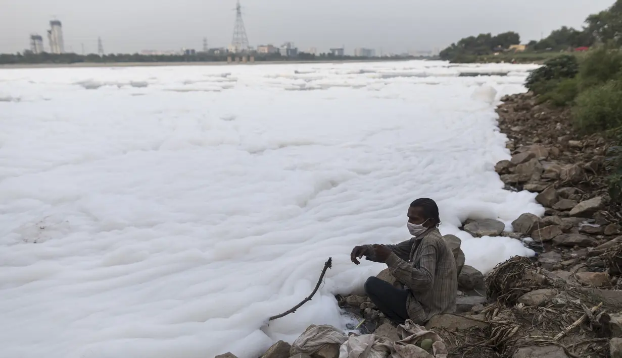Seorang nelayan menarik tali pancing di tengah buih di sepanjang tepi sungai Yamuna yang tercemar di pinggiran New Delhi (23/7/2020). Sungai ini menyandang gelar sebagai sungai paling tercemar di dunia. (AFP Photo/Xavier Galiana)