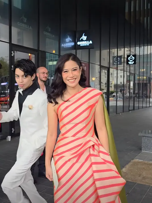 Dian Sastrowardoyo kenakan one shoulder striped gown peach gold satin dengan rok lebar yang dilipit samping [@therealdisastr]