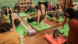 Orang-orang melakukan meditasi dalam kelas yoga bersama kucing  di kafe kucing Brooklyn, New York, Rabu (13/3). Kafe ini menawarkan tempat latihan yoga dengan ditemani kucing-kucing menggemaskan. (REUTERS/Jeenah Moon)